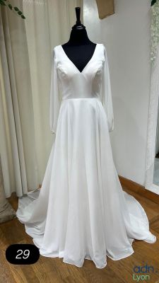 La robe de mariée est posée sur un mannequin devant une vitrine.
