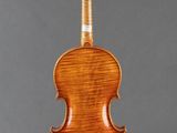 an antique violin on a stand with a gray background