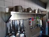 pots and pans are hanging on a metal shelf in a kitchen