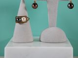 une paire de boucles d'oreilles et une bague posées sur un présentoir posé sur une table