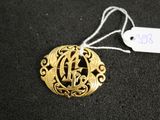 a close up of a gold necklace with a monogram on it