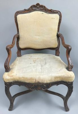 an old chair with a beige upholstered seat and a wooden frame