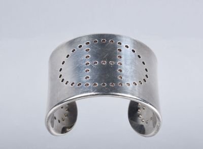 a close up of a silver cuff with holes on it