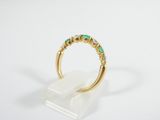 a close up of a gold ring with green stones on it