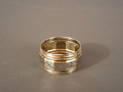 une bague en or posée sur une table avec un fond argenté
