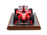 the model of a red race car is on display on a wooden stand