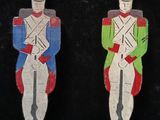 two wooden toy soldiers are standing next to each other on a black surface