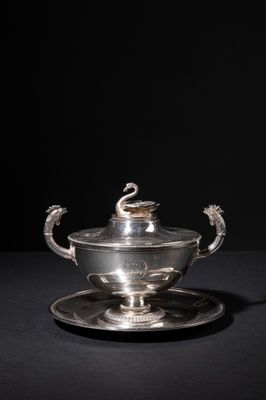 a silver plate with a bowl and saucer on a black surface