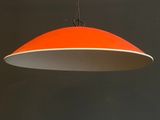 an orange and white pendant light hanging from a black wall