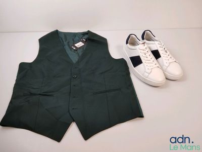 un gilet vert et une paire de baskets blanches posés sur une table