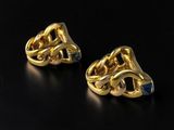 a pair of gold earrings on a black surface