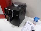 a black coffee machine sitting on a counter next to a red box
