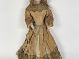 une poupée à l'ancienne, vêtue d'une robe marron et d'un chapeau marron