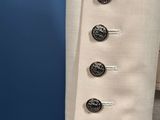 a close up of a white jacket with buttons on it