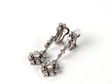 une paire de boucles d'oreilles en diamant posées sur une surface blanche, sur fond blanc