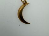 a close up of a gold crescent charm on a white surface