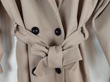 a close up of a coat on a hanger on a white wall