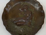 une sculpture en bronze représentant une femme assise sur un plateau