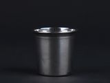 a close up of a metal cup on a black background