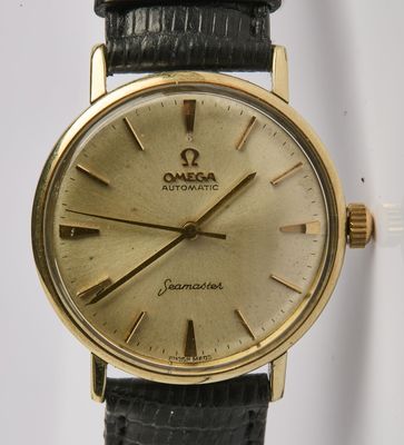 une montre en or avec un bracelet noir sur fond blanc