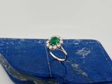 une bague sertie d'une émeraude et de diamants, posée sur une pierre bleue