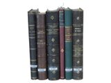several books are stacked on top of each other on a white surface