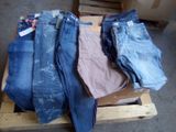 Plusieurs paires de jeans sont empilées sur une palette dans un entrepôt