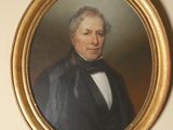 portrait d'un homme vêtu d'un manteau noir et d'un nœud papillon, dans un cadre doré