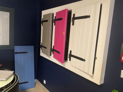 Des volets aux couleurs vives sont accrochés au mur d'une salle de bains