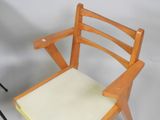 a wooden chair with a cushion on it next to a tripod