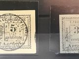 Deux timbres sont exposés dans une vitrine posée sur une table