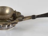 une théière ancienne en laiton, avec une anse noire sur un fond blanc