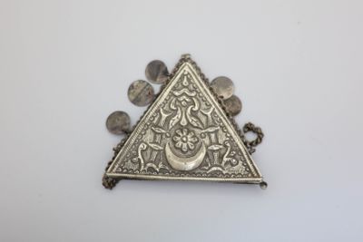 an image of a triangle shaped silver broochle on a white surface