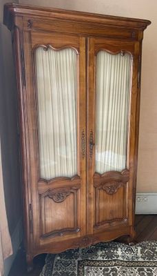 a wooden armoire with two doors and a rug on the floor
