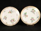two plates with floral designs on them are sitting on a black surface