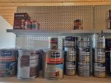 many cans of paint sitting on a shelf in a room