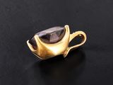 a close up of a gold plated pendant with a black stone