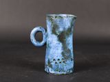 a blue vase with a handle on a table