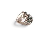 a close up of a ring with green stones on a white background