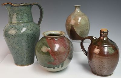 trois vases et une cruche sont posés sur une surface blanche