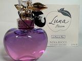 un flacon de parfum en verre violet orné d'une feuille d'or sur le bouchon, à côté d'une carte de visite