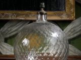 un vase en verre posé sur une table, avec un tableau en arrière-plan