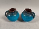 pair of blue and brown vases with handles on a white surface