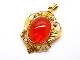 une image représentant un pendentif doré et rouge orné de perles, sur fond blanc