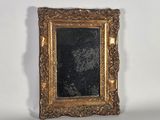 an old picture frame with a black and gold picture in it