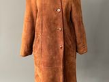 un manteau marron posé sur un pied de mannequin, sur un fond gris