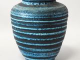 un vase bleu et noir posé sur une surface blanche
