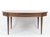 une table à manger ovale avec un plateau en bois et une bordure en laiton