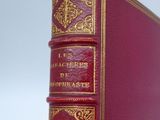 an old red book sitting on top of a wooden table