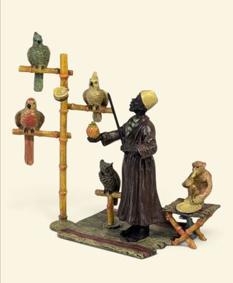 figurine représentant un moine avec un chat et des oiseaux, posée sur un socle